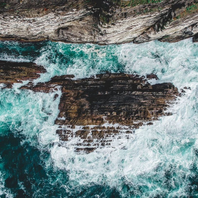 Drone Photography featuring waves crashing on cliffs