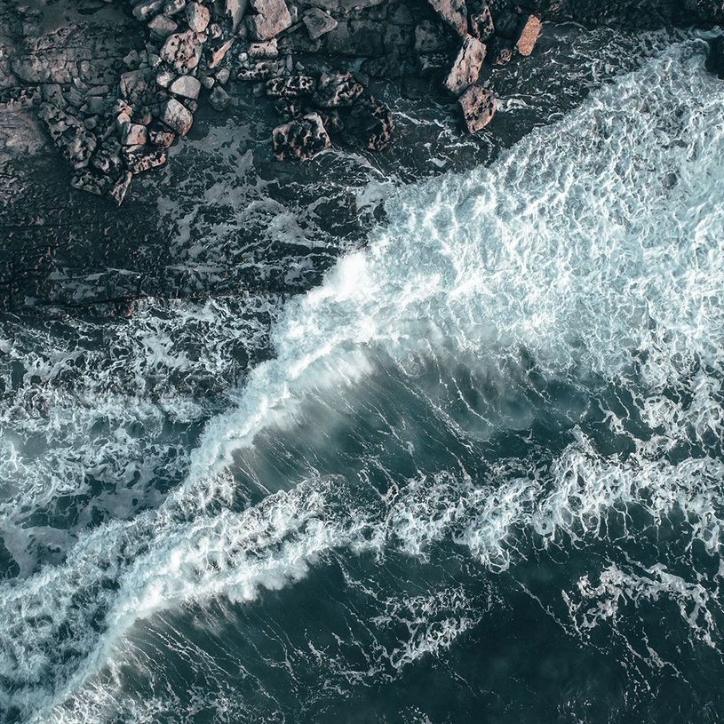 Aerial Photography of waves crashing at the bottom of a cliff